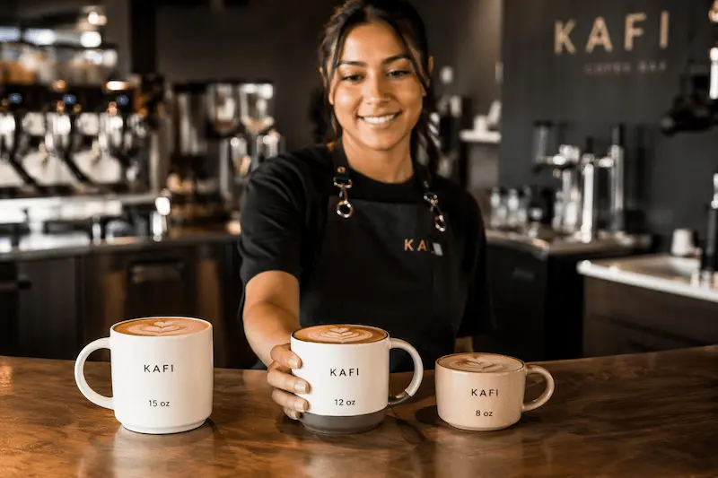 Barista serving coffee in different sized ceramic mugs